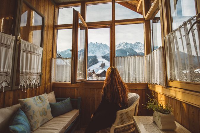 Woman sitting on  armchair looking at mountains through the window