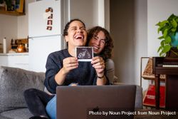 Two women happy sharing their  sonogram picture over video chat 4jWRxb