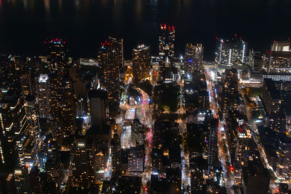Top Down Aerial View of New York City Streets Lit with Neon Lights from Billboards. Busy Metropolis Traffic with Cars, Yellow Taxis, Commercial Vehicles and People Walking
