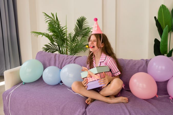 Young girl celebrating her birthday at home, holding presents.