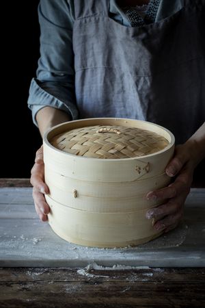 Person holding a bamboo steamer
