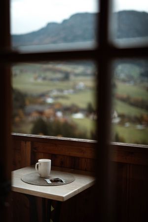 Small table with cup of coffee and photos on terrace on cloudy morning