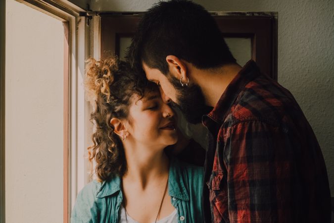 Happy couple embracing on window sill at home