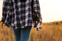 Unrecognizable woman taking photos with analog camera in the countryside