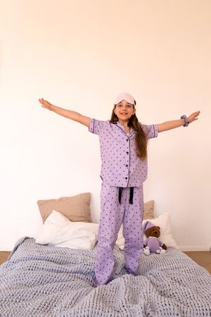 Girl with arms spread wide on bed