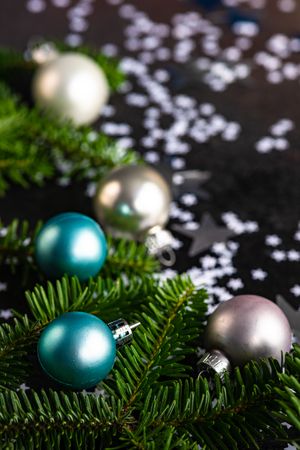 Christmas card concept of blue and silver baubles on table with pine and star confetti