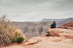 Female relaxing on cliff and admiring picturesque view
