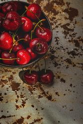 Juicy red cherry in bowl on rustic surface