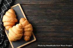 Bread board with croissants on table with kitchen towel, top view with copy space 4AaB84