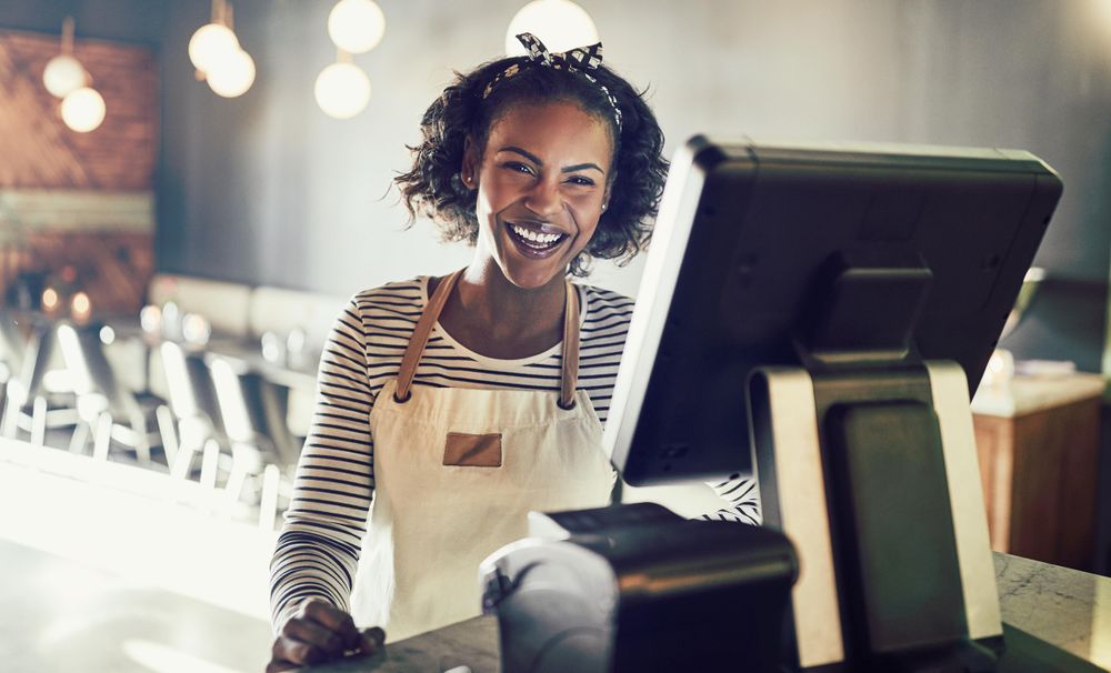Happy woman at modern cash register taking orders in bistro