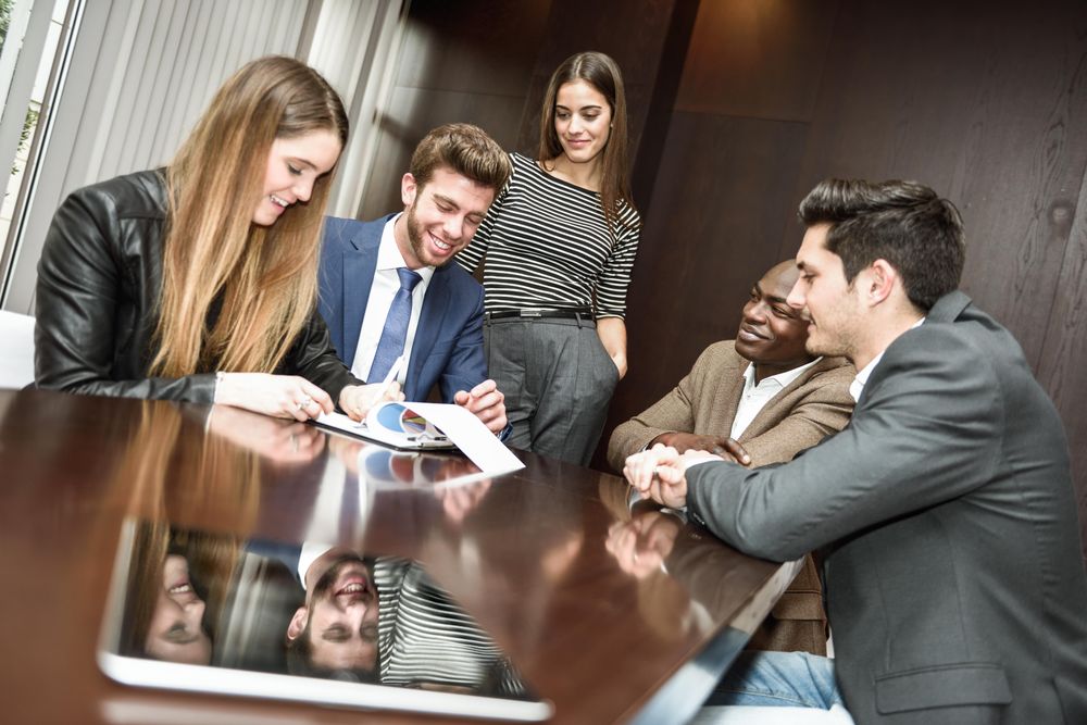 Male and female co-workers working on charts and graphs in a meeting room