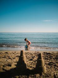 Sandy little towers and girl on seaside