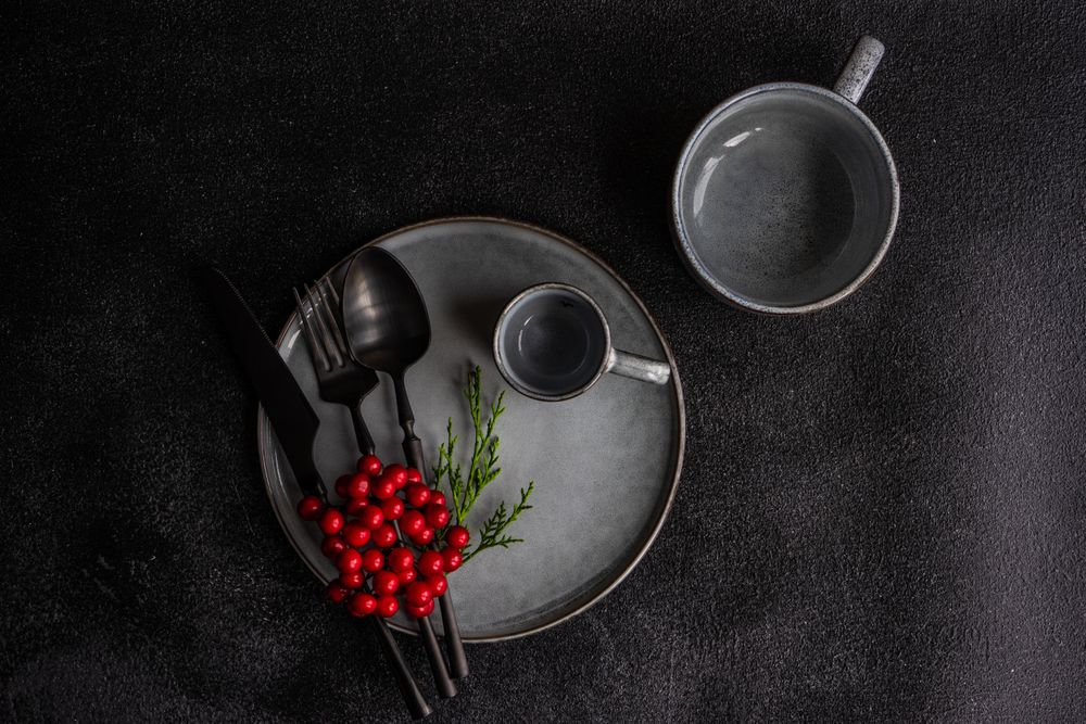 Top view of grey plate and mug surrounded by seasonal red berries
