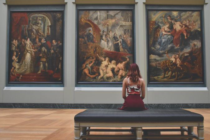 Back view of woman sitting on couch in museum
