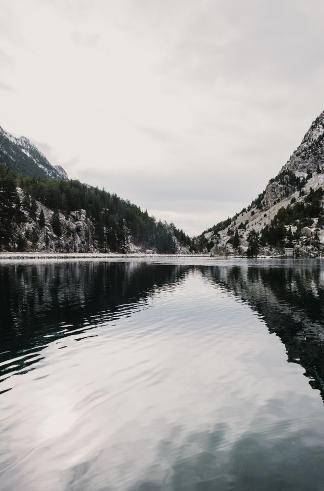 Wonderful lake between hills in snow and cloudy sky