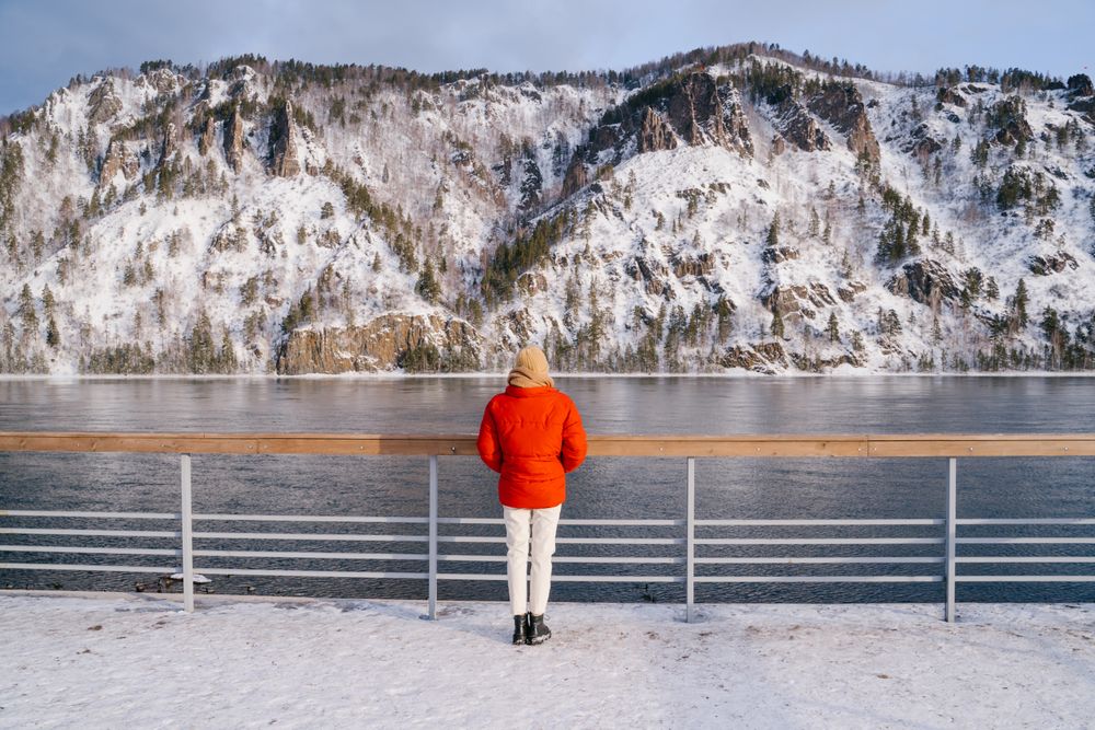 Woman enjoying landscape of river and snowy mountains