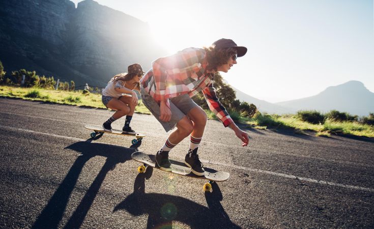 Side portrait of young people skateboarding together on road