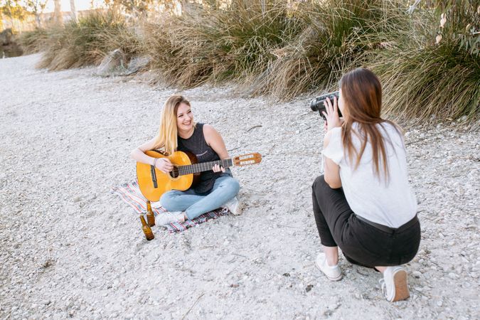 Young woman shooting friend playing guitar