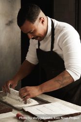 Black male chef working with powdered sugar to top chocolate slices with 5nLGmb