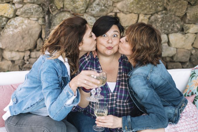 Portrait of three funny woman having fun kissing friend outdoors