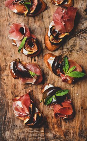 Crostinis with prosciutto, goat cheese and grilled figs on wooden board