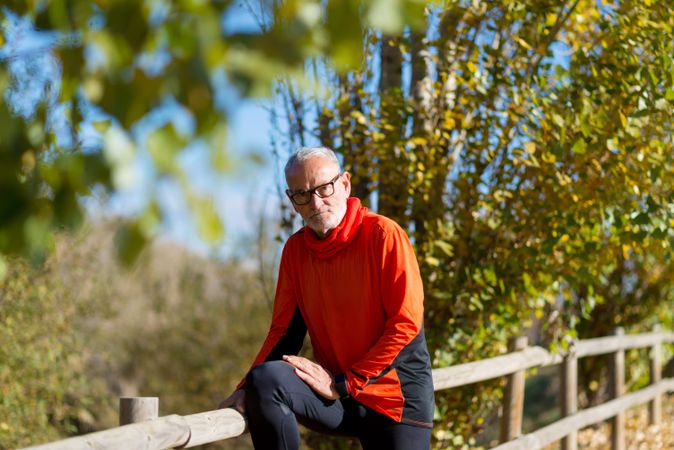 Older male stretching legs on wooden fence