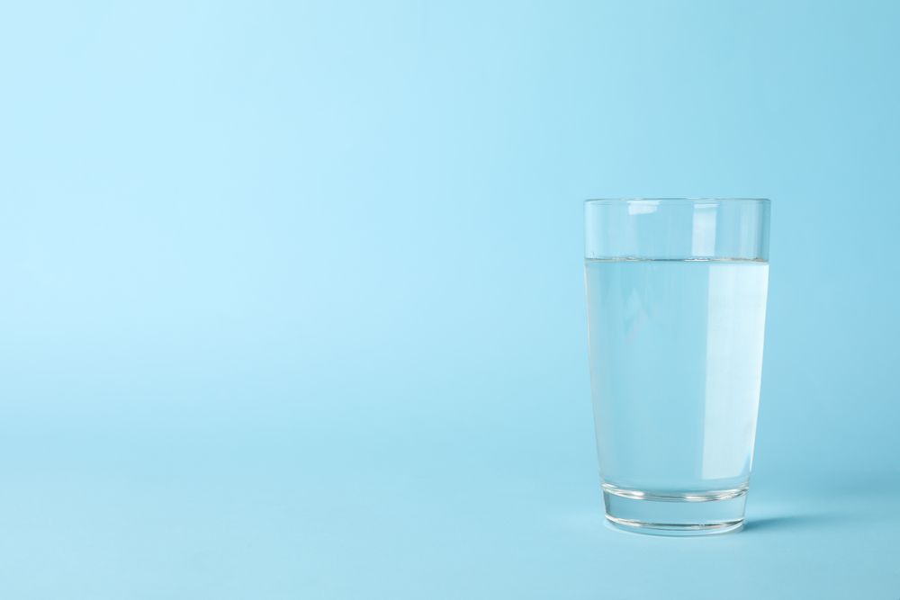 Full glass of water in light blue room