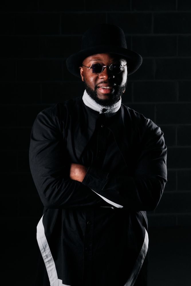 Black man in trendy outfit on dark background