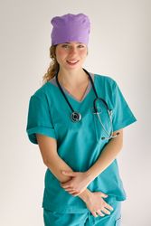Glad female doctor in cap and uniform on gray background