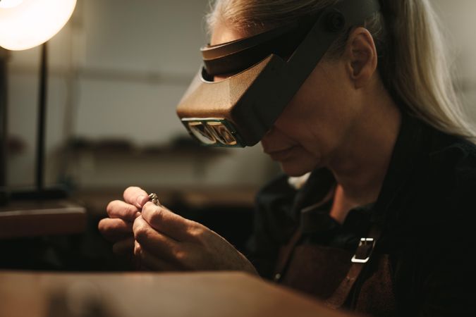 Close up of female jeweler examining a ring with magnifying glass