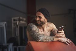 Laughing athlete with smartphone in gym