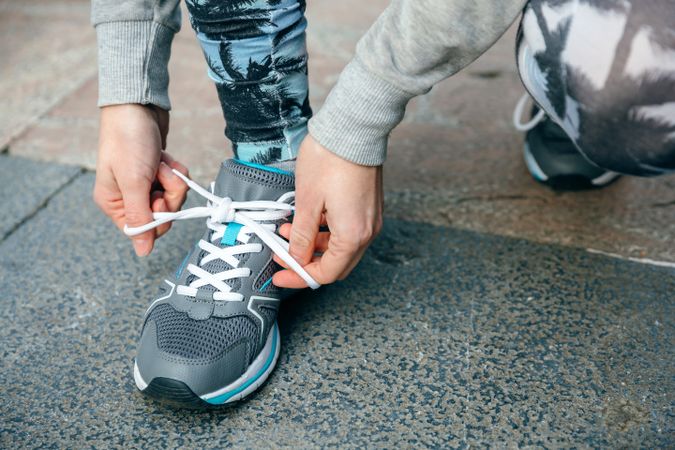 Close up of female runner tying her sneakers laces to training