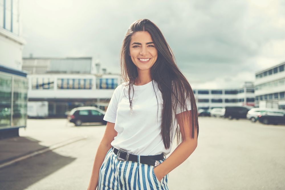 Portrait of woman in striped blue trousers smiling outside on the street