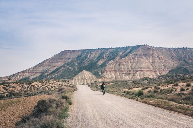Man riding bicycles on road in desert hills