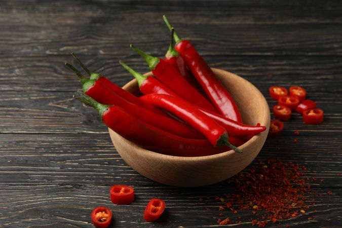 Spices and bowl with chilli pepper on wooden background