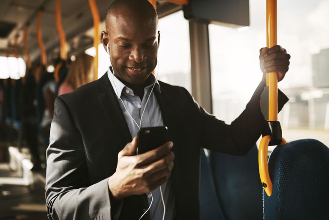 Man in business attire listening to phone on public transport