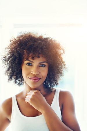 Portrait of smiling curly haired female in vest in a bright room