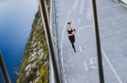 Young woman running on embankment near water