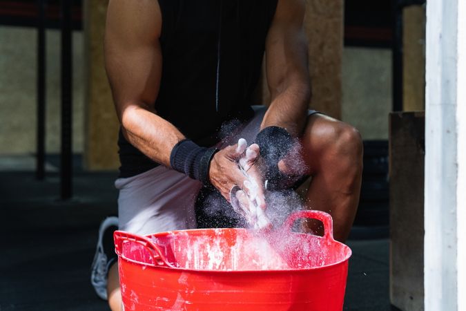 Unrecognizable sportsman near bucket with talc