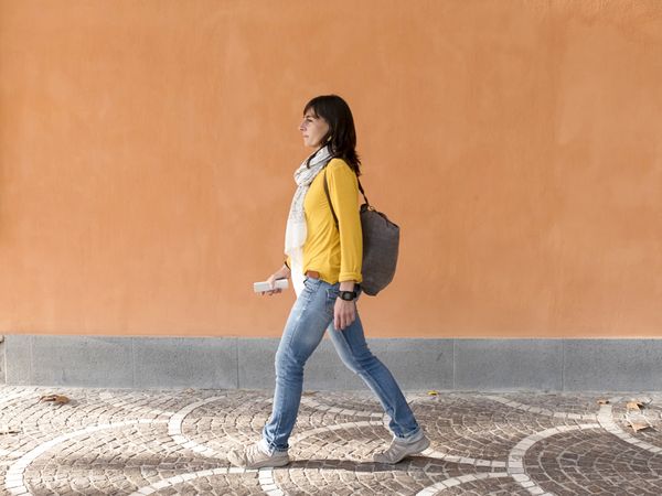 Side view of a backpacker traveler walking against orange wall in the city