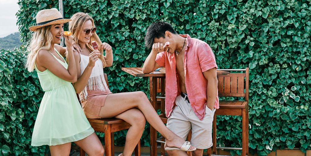 a young man laughing with two women