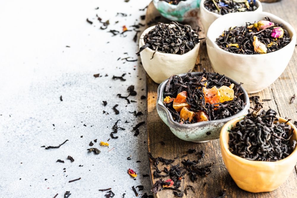 Tea leaves in bowls on marble background with copy space