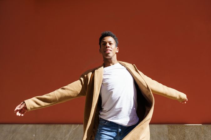 Black male in camel coat with his arms open