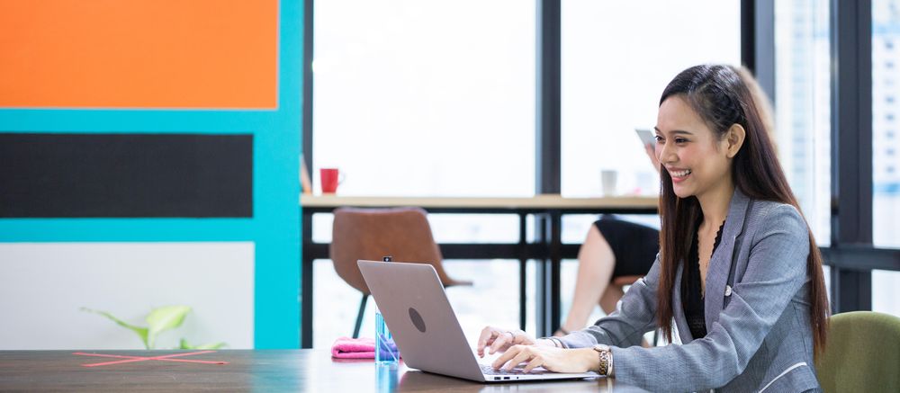 Asian female employee using computer laptop working in co-working space at the office