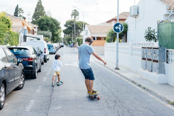 Man skating down road with son