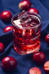 Red beverage near fresh fruits on cloth