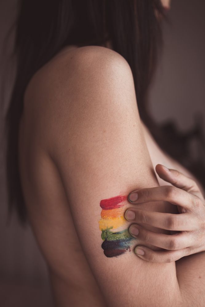 naked woman covering breast and drawing LGBTQIA symbol