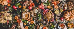 Group of people at festive table setting with roast chicken, squash, and pie, wide composition