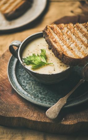 Close up of celery soup in cup with toast, and spoon