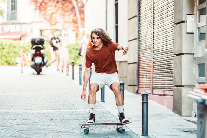 Confident man riding longboard across city street